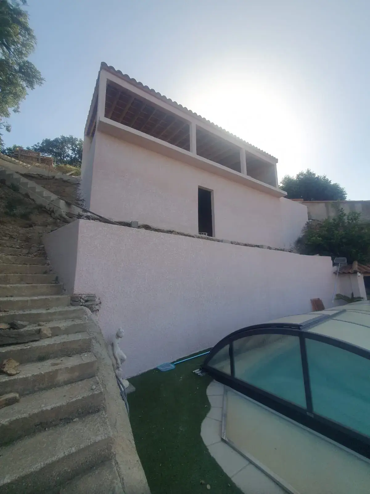 Extension en coteau, terrasse couverte et escaliers en béton